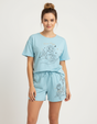 Woman wearing a light blue pajama set with floral designs on a white background