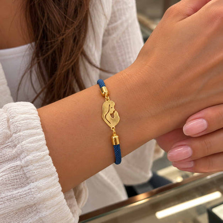 Blue braided cord bracelet with a gold mother holding her baby charm on a wrist