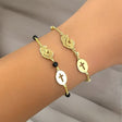 Gold bracelet with Mother Mary symbol on a wrist against a neutral background