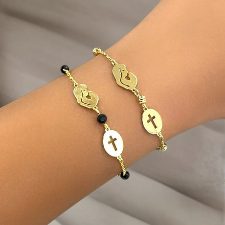 Gold bracelet with Mother Mary symbol on a wrist against a neutral background