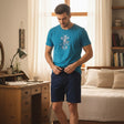Man wearing a teal cartoon chef mouse tee with navy shorts
