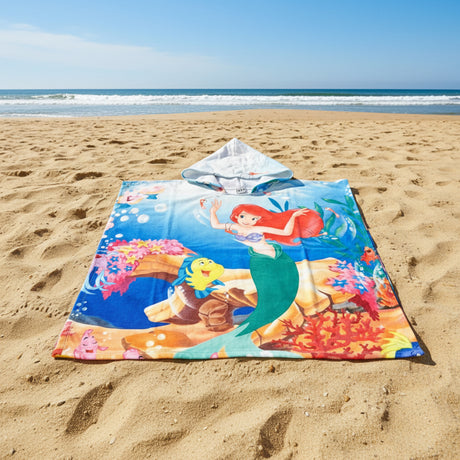 Mermaid poncho towel with a coral reef seabed print and pale blue hood flat lay on sand