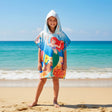 Girl wearing a hooded mermaid poncho with a red haired mermaid and yellow fish on a reef