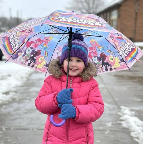 Girl outdoors under an open My Little Pony kids umbrella with a rainbow print