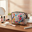 Cosmetic bag with 'Nail Stuff' design on a wooden table with nail polish and tools.