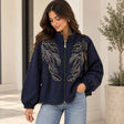 Woman in a navy zip jacket with silver beaded leaf sprays, balloon sleeves and a lace trimmed hem