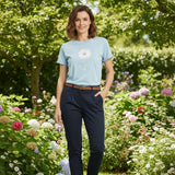 Woman standing in a garden wearing a light blue tshirt and navy pants