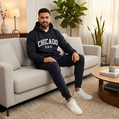 Man sitting on a couch wearing a navy 'Chicago USA' hoodie and sweatpants in a living room