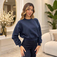 Woman in a navy cropped crew neck sweatshirt with balloon sleeves and dark high waisted jeans