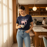 Woman holding a mug in a kitchen wearing a navy blue tshirt with an elephant graphic