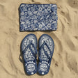Blue floral-patterned pouch and flip-flops on sand