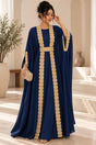 Woman in a navy batwing kaftan with gold lace trim and a gold belt in a bright room