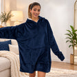 Woman in a navy fleece hooded blanket with arms outstretched in a bright living room