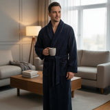 Navy ribbed robe worn with the belt tied, holding a mug by a bright window