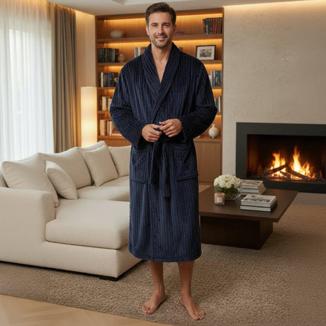 Man wearing a navy ribbed bathrobe by a lit fireplace