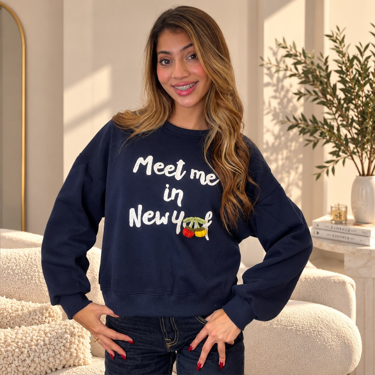 Woman with hands on hips in a navy Meet me in New York sweatshirt with cream lettering