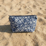 Blue floral-patterned pouch on sandy ground