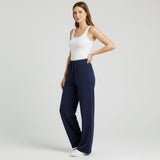 Woman wearing navy wide-leg pants and a white tank top on a light gray background