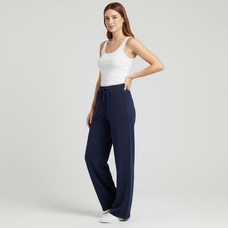 Woman wearing navy wide-leg pants and a white tank top on a light gray background