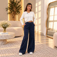 Woman in navy wide leg sweatpants with a drawstring waist and a cream hoodie
