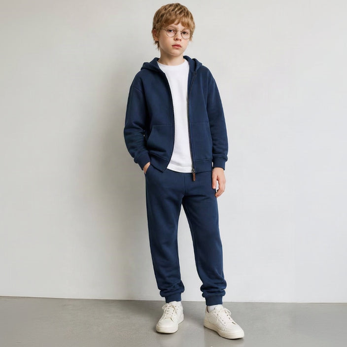 Boy in glasses wearing a navy zip hoodie and joggers over a white tee