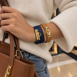 Woman wearing navy and camel wrap bracelets with gold pyramid studs, stacked on her wrist with a cream sweater