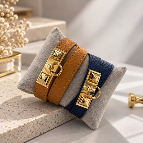 Navy and Camel pyramid stud wrap bracelets with gold ring clasps displayed on a grey velvet cushion