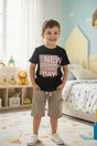 Boy in a black New Beginnings slogan tee and khaki cargo shorts
