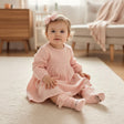 Infant in a blush dress wearing a pale pink tulle bow headband with matching face print knee socks