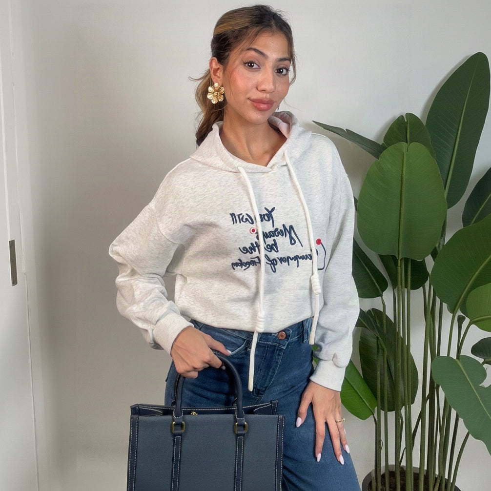 Oatmeal cropped hoodie worn with jeans and a navy tote in a bright room
