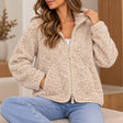 Oatmeal speckled teddy fleece jacket with a high zip collar and piped pockets, worn seated with light jeans