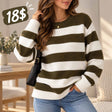Woman in an olive green and white wide striped wool sweater and jeans with a black shoulder bag