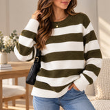 Woman in an olive green and white wide striped wool sweater and jeans with a black shoulder bag