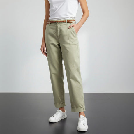 Person wearing olive green pants, white shirt, and white sneakers on a gray background