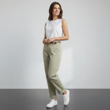 Person wearing olive green pants and white sneakers on a gray floor with white background