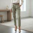 Person wearing olive green pants and a white shirt in a minimalistic room