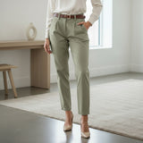 Person wearing olive green pants and a white shirt in a minimalistic room
