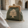 Olive green cedar embroidered clutch with a wooden clasp frame and long gold chain under stone arches