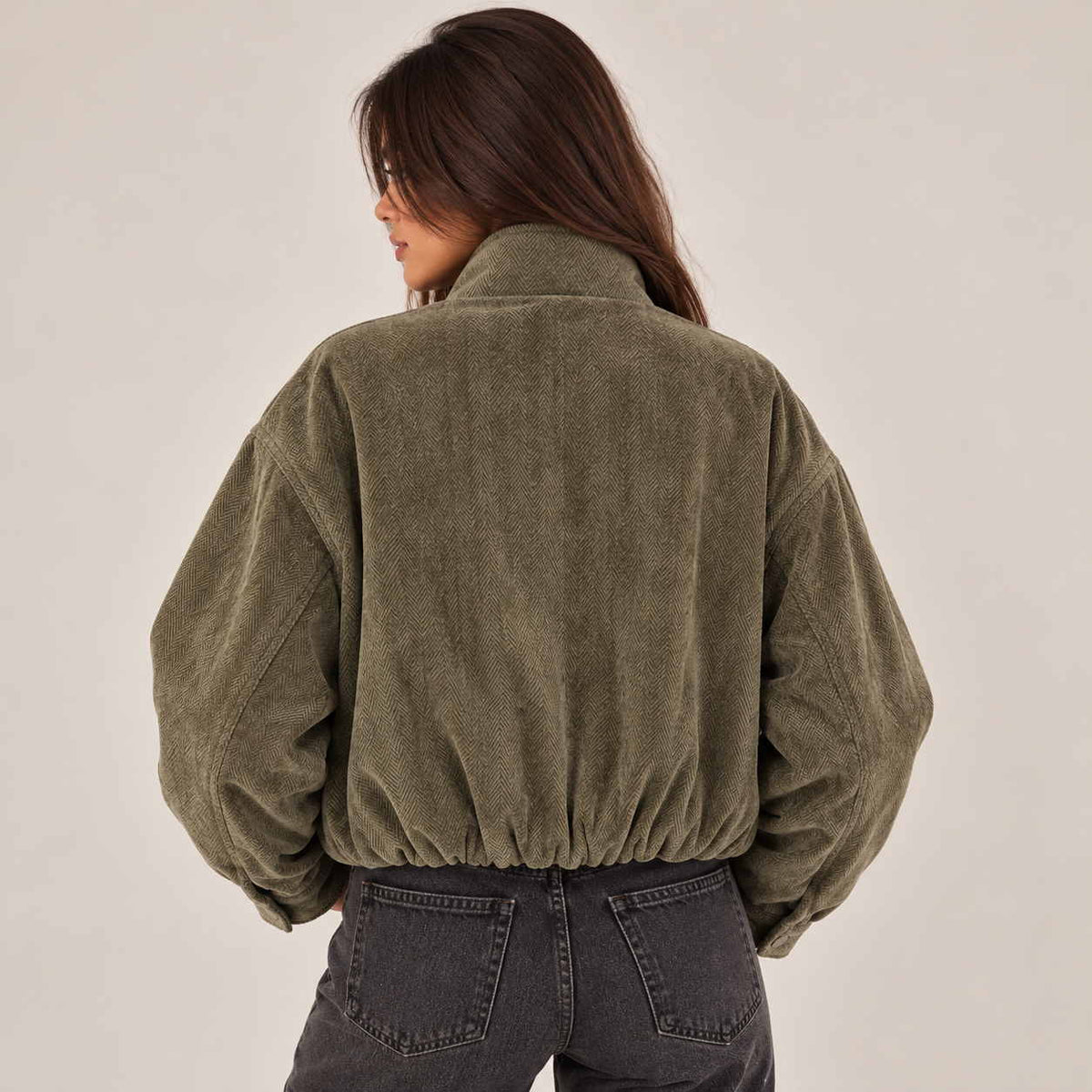 Back view of an olive herringbone jacket with gathered elastic hem