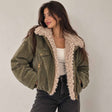 Olive herringbone jacket with fluffy cream sherpa collar worn over a white tank top