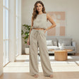 Woman wearing a light olive sleeveless top and pants in a modern living room