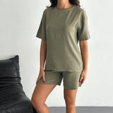 Person wearing an olive green tshirt and shorts set in a minimalistic setting