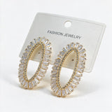 Gold open oval earrings with clear baguette stones and a pave inner edge on a card