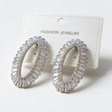 Pair of silver tone open oval baguette crystal earrings on a white display card