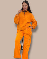 Woman wearing an orange lounge set against a beige background