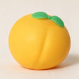 Round orange peach squishy with two green leaves and a soft centre crease