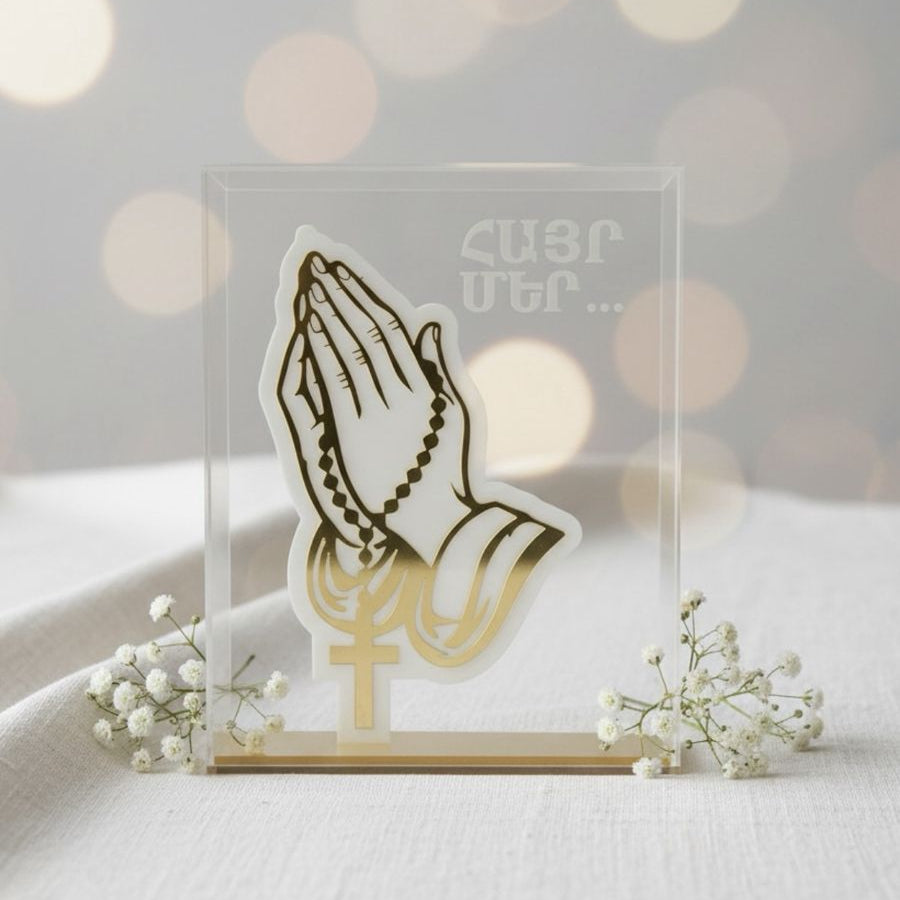 Clasped hands and a rosary in frosted acrylic beside etched Armenian script