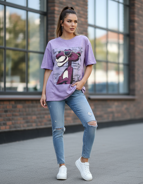 Woman wearing a purple graphic tshirt and ripped jeans standing in front of a brick building