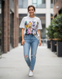 Woman wearing a graphic tshirt of cartoon characters and ripped jeans walking outdoors