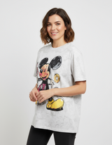 Woman wearing a white tshirt with a cartoon character design on a plain background